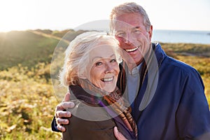 Portrait Of Loving Active Senior Couple Walking Along Coastal Path In Autumn Together