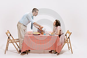 Portrait of loving couple sitting at the table, having breakfast  on white background. Look of love