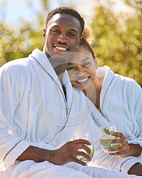 Portrait Of Loving Couple Wearing Robes Outdoors With Drinks On Spa Day