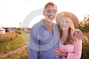 Portrait Of Loving Mature Couple In Countryside Hugging Against Flaring Sun