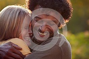 Portrait Of Loving Mature Couple Hugging Outdoors Against Flaring Evening Sun