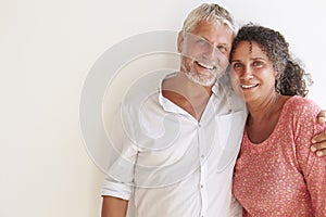 Portrait Of Loving Mature Couple Standing Against Wall