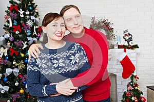 Portrait of loving middle aged couple in living room with christmas tree and decorated fireplace, loving family