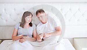 Portrait of loving middle aged couple smiling and watching something on a mobile phone in bedroom