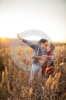 Portrait of loving middle-aged couple in warm clothes hugging in the autumn park at sunset in selective focus