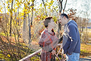 Portrait of loving middle-aged couple in warm clothes hugging in the autumn park at sunset in selective focus