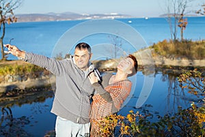 Portrait of loving middle-aged couple in warm clothes hugging in the autumn park at sunset in selective focus