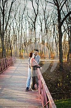 Portrait of loving middle-aged couple in warm clothes hugging in the autumn park at sunset in selective focus