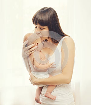 Portrait of loving mom kissing little baby