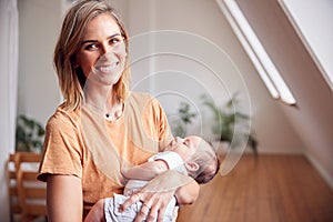 Portrait Of Loving Mother Holding Newborn Baby At Home In Loft Apartment