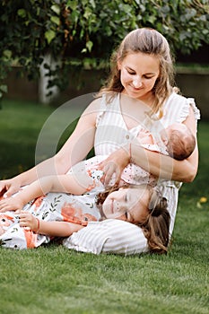 Portrait of loving mother and two adorable kids. little girl and newborn baby girl with mom outdoors on summer day. Happy family