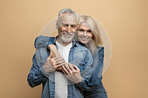 Portrait of loving senior couple bonding on colorful background