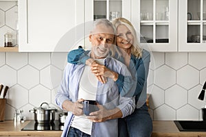 Portrait Of Loving Senior Couple Relaxing With Coffee In Kitchen Interior