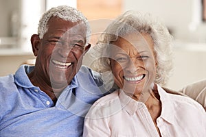 Portrait Of Loving Senior Couple Sitting On Sofa At Home Together