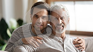 Portrait of loving senior dad and adult son hugging