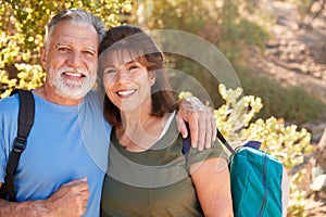 Portrait Of Loving Senior Hispanic Couple Hiking Along Trail In Countryside Together