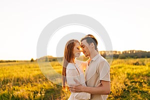 Portrait of loving young couple in relationship hugging and kissing enjoying each other in wonderful sunlight of sunset