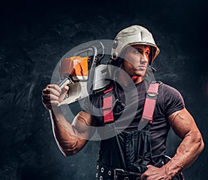 Portrait of a lumberjack wearing protective clothes posing with a chainsaw