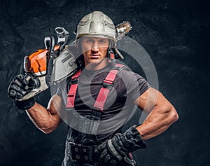 Portrait of a lumberjack wearing protective clothes posing with a chainsaw