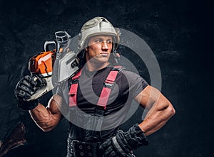 Portrait of a lumberjack wearing protective clothes posing with a chainsaw