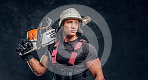 Portrait of a lumberjack wearing protective clothes posing with a chainsaw