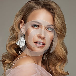 Portrait of luxury blonde woman with perfect makeup posing holding pink rose