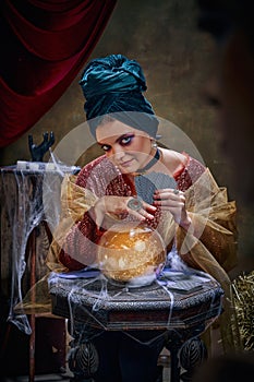 Portrait of magnificent fortune teller woman reading future on magical crystal ball and tarot cards. Concept of vintage