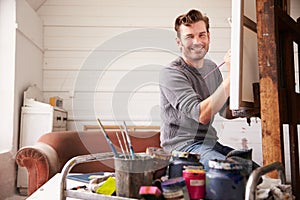 Portrait Of Male Artist Working On Painting In Studio