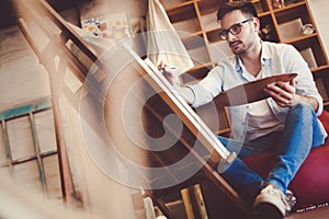 Portrait Of Male Artist Working On Painting In Studio