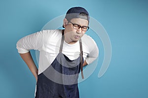 Portrait of male Asian chef or waiter suffer from low back pain, tired expression