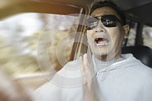 Portrait of male Asian driver shocked and panic about to have crash accident, zoomed motion blur defocus