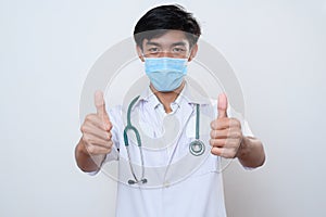 Portrait of male asian young doctor with thumbs up wears medical face mask