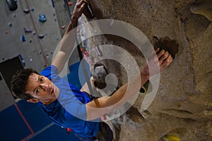 Portrait of male athlete climbing wall in fitness studio