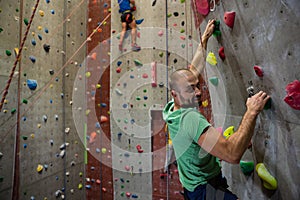 Portrait of male athlete climbing wall in health club