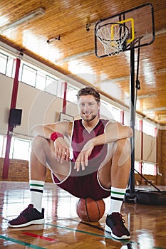 Portrait of male basketball player sitting on ball