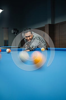 portrait of the male billiard player smiling while poking the ball