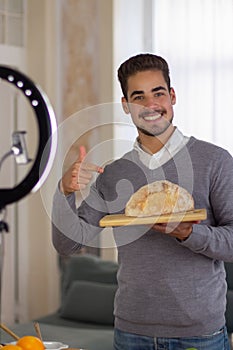 Portrait of male blogger offering healthy self-cooked bread photo