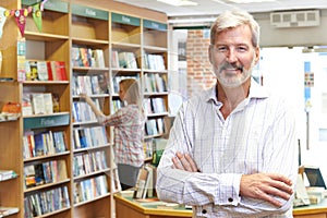 Portrait Of Male Bookstore Owner With Customer In Background