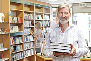 Portrait Of Male Bookstore Owner With Customer In Background