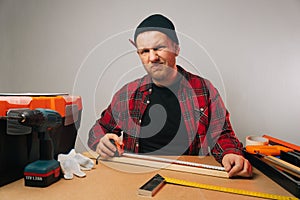 Portrait of a male builder with a beard in uniform who is in doubt. Woodworking workshop in a factory
