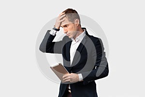 Portrait of a male businessman shocked by the crisis from the coronavirus and financial losses, holds his hand on head