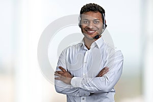 Portrait of male call center agent looking at camera with crossed arms.