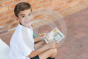 Portrait of male caucasian student having a video call with female teacher on digital tablet at scho