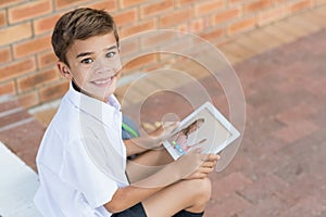 Portrait of male caucasian student having a video call with female teacher on digital tablet at scho