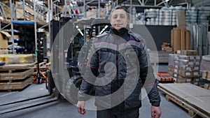 Portrait of male Caucasian warehouse worker standing indoors looking at camera. Adult man in uniform posing at workplace