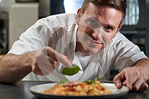 Portrait Of Male Chef Garnishing Plate Of Food In Professional Kitchen photo
