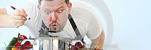 Portrait of male chef preparing and tasting hot food in vegetable soup spoon