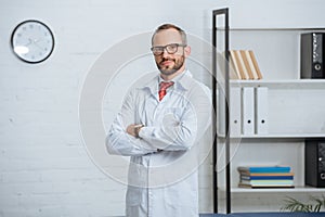 portrait of male chiropractor in white coat and eyeglasses with arms crossed