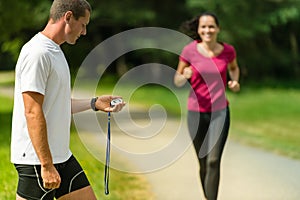 Portrait of male coach timing runner outdoors