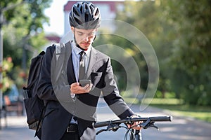 Portrait of a male commuter in a suit and bicycle helmet with a phone.